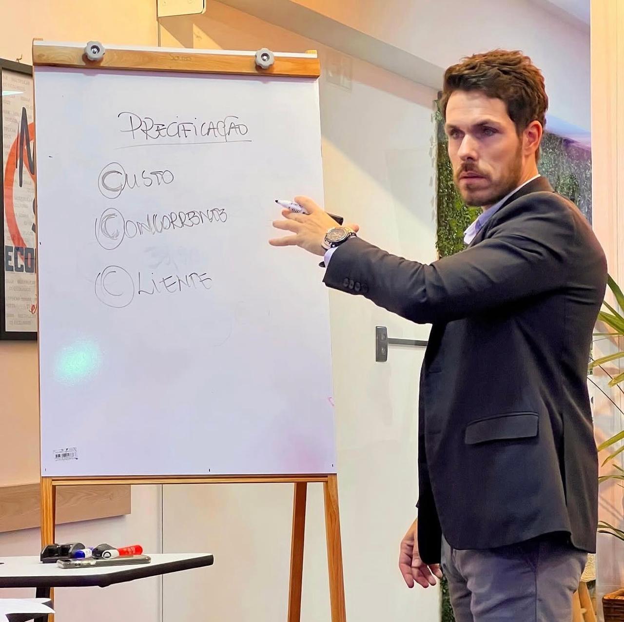 Luiz Benevenuto conduzindo um treinamento diante de um quadro